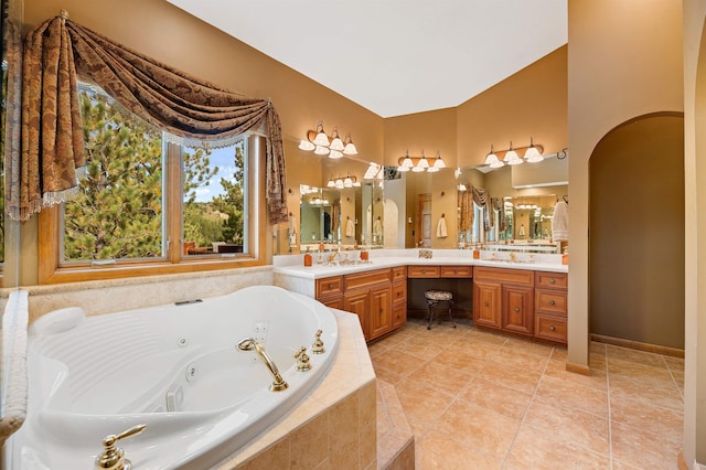 bathroom with tile patterned floors, vanity, lofted ceiling, and tiled bath