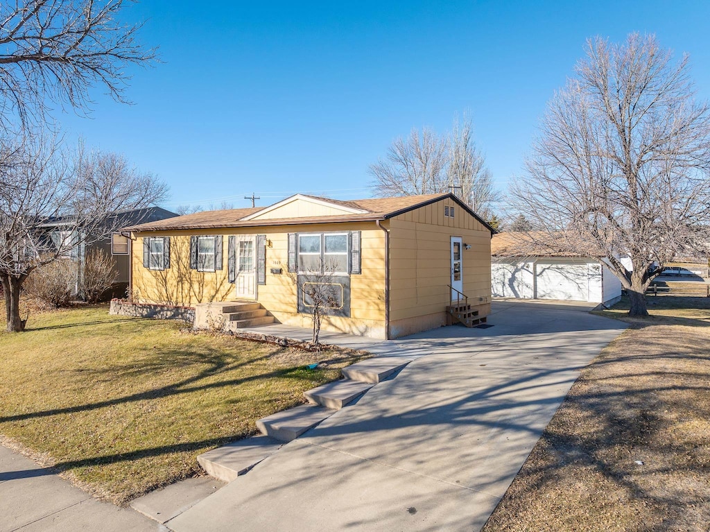 single story home featuring a garage, an outdoor structure, and a front yard