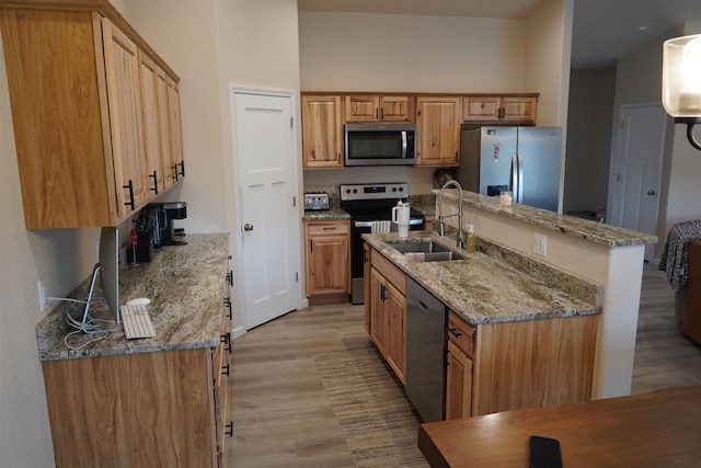 kitchen featuring light stone countertops, sink, light hardwood / wood-style floors, and appliances with stainless steel finishes