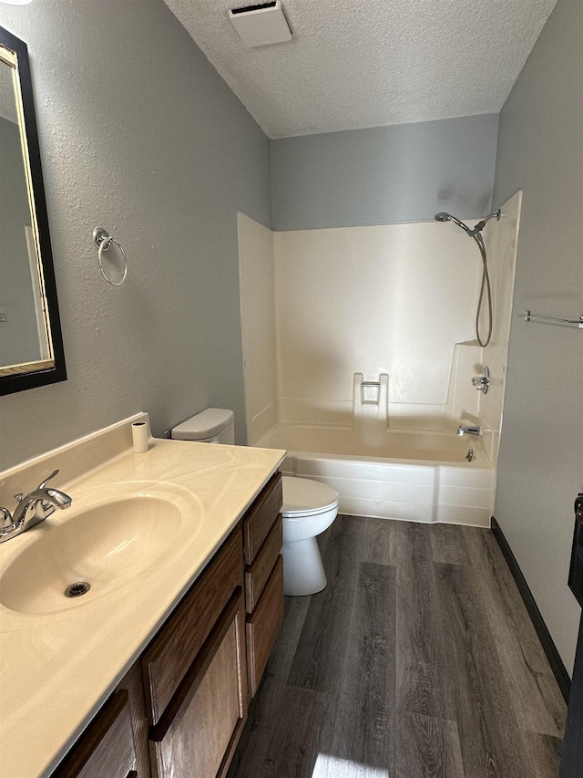 full bathroom with shower / bath combination, vanity, a textured ceiling, hardwood / wood-style floors, and toilet