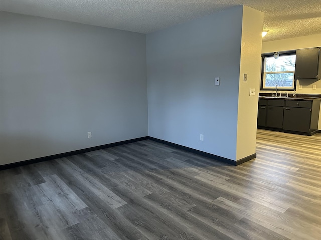 unfurnished room featuring a textured ceiling, hardwood / wood-style flooring, and sink