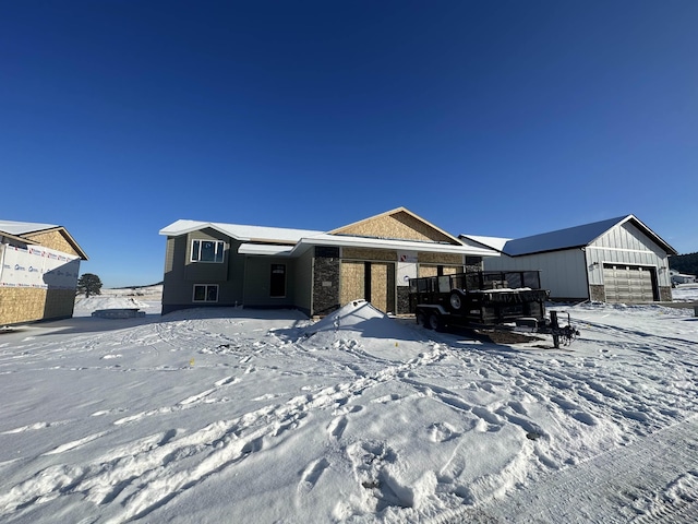 view of front of home with a garage, an outbuilding, stone siding, and board and batten siding