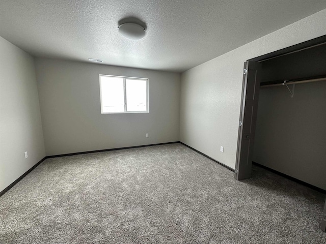 unfurnished bedroom featuring carpet flooring, visible vents, baseboards, and a textured ceiling