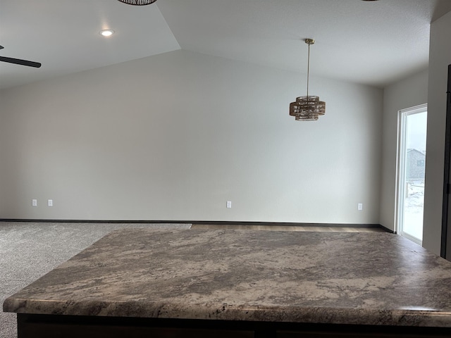 empty room with lofted ceiling, carpet flooring, ceiling fan, and baseboards