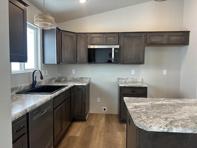 kitchen featuring lofted ceiling, stainless steel appliances, a sink, and dark brown cabinetry