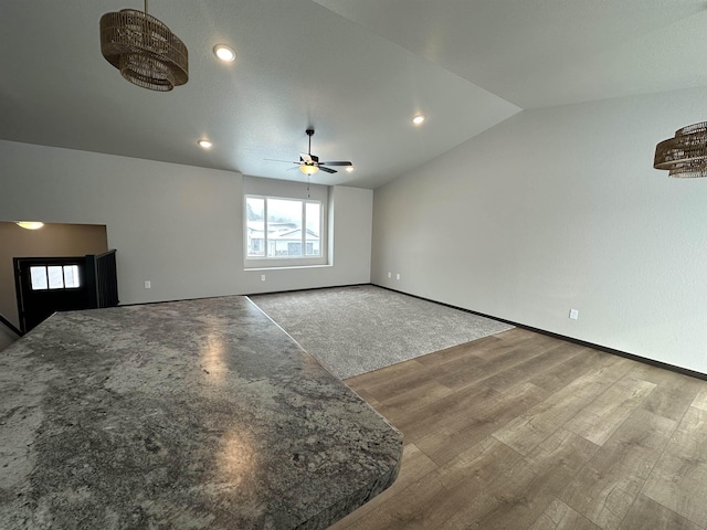 living area featuring lofted ceiling, baseboards, a ceiling fan, and wood finished floors