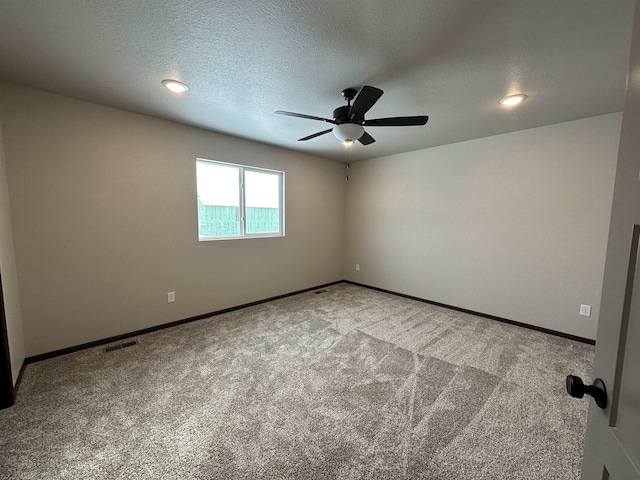 carpeted spare room featuring a textured ceiling, ceiling fan, visible vents, and baseboards