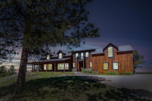 view of front of property featuring a lawn and a balcony