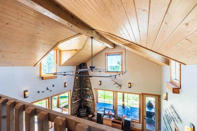 interior space with beamed ceiling, a wood stove, a wealth of natural light, and wooden ceiling