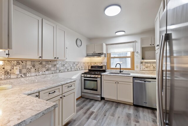 kitchen with backsplash, white cabinets, sink, light hardwood / wood-style flooring, and stainless steel appliances