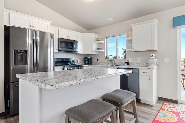 kitchen with white cabinets, stainless steel appliances, a kitchen island, and sink