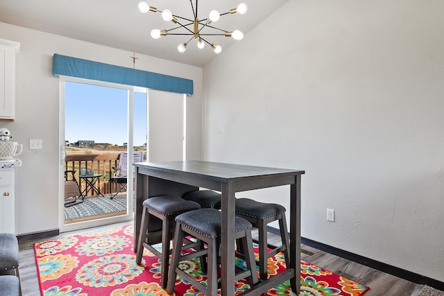 dining room featuring hardwood / wood-style floors, lofted ceiling, and a chandelier