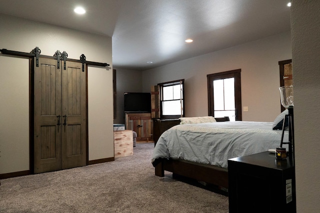 bedroom featuring light carpet and a barn door