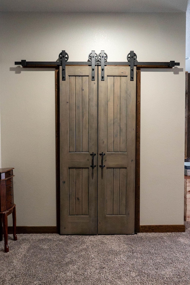 interior details with a barn door and carpet floors