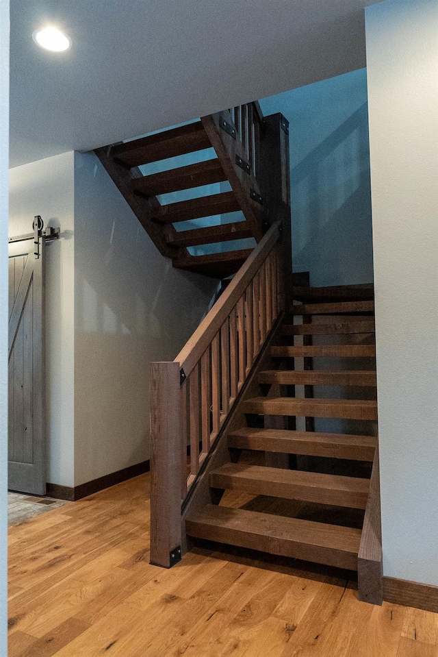 stairway featuring a barn door and hardwood / wood-style flooring