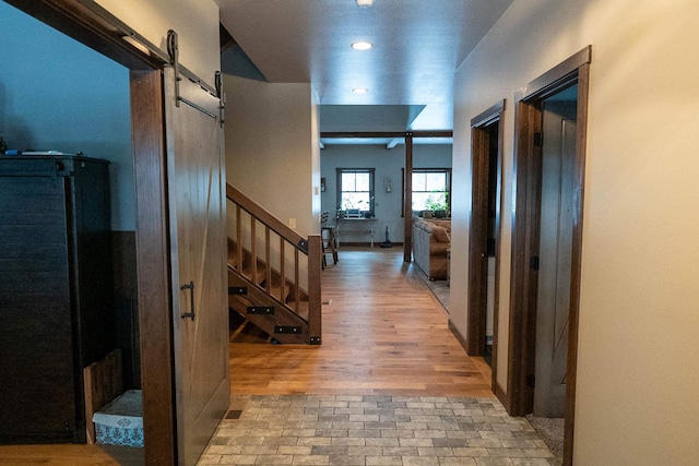 corridor featuring a barn door and light wood-type flooring