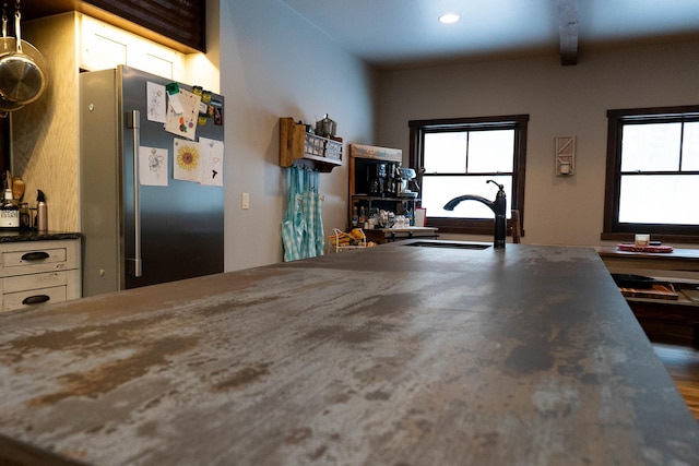 kitchen with stainless steel fridge, sink, beamed ceiling, and hardwood / wood-style floors