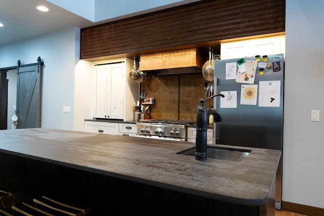 kitchen with stainless steel fridge, a barn door, kitchen peninsula, and sink