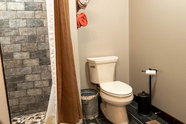 bathroom featuring toilet and curtained shower