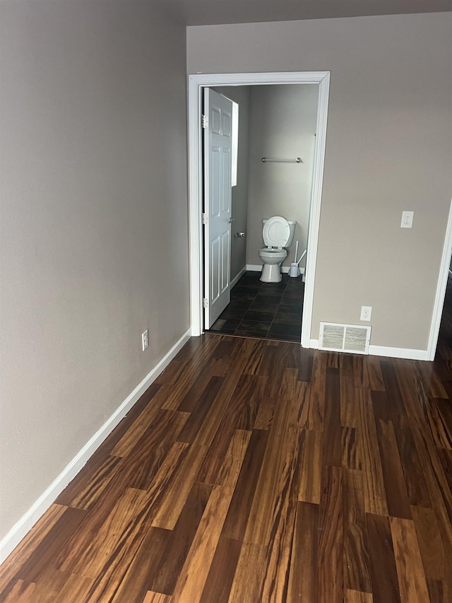 unfurnished bedroom with dark hardwood / wood-style flooring and ensuite bath