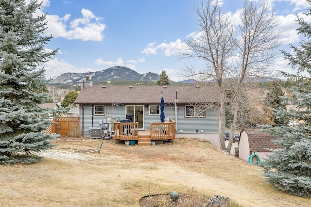 back of property featuring central AC, a deck with mountain view, and a shed