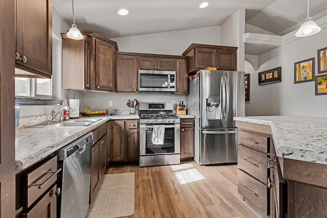 kitchen featuring pendant lighting, light wood-type flooring, lofted ceiling, and appliances with stainless steel finishes