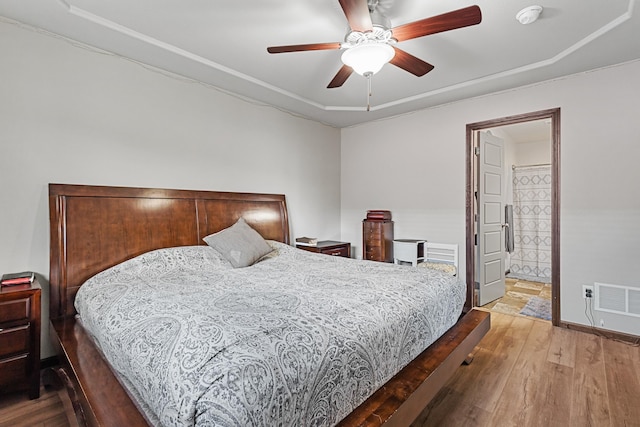 bedroom with hardwood / wood-style floors, ensuite bathroom, and ceiling fan