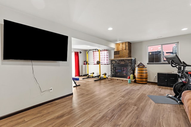 exercise room featuring light wood-type flooring and a fireplace