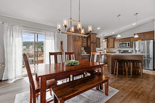 dining area featuring a notable chandelier, lofted ceiling, and hardwood / wood-style flooring