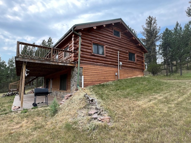 view of side of property featuring a wooden deck, a yard, and a patio