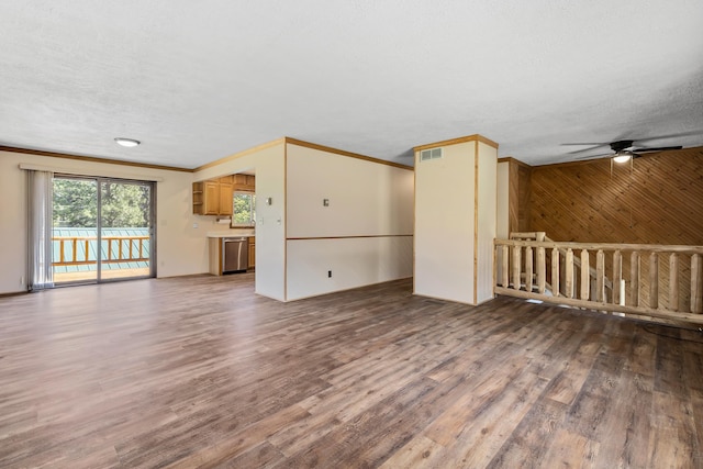 unfurnished living room with a textured ceiling, ceiling fan, wooden walls, crown molding, and hardwood / wood-style flooring