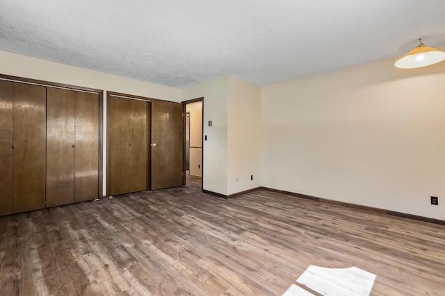 unfurnished bedroom with multiple closets and dark wood-type flooring