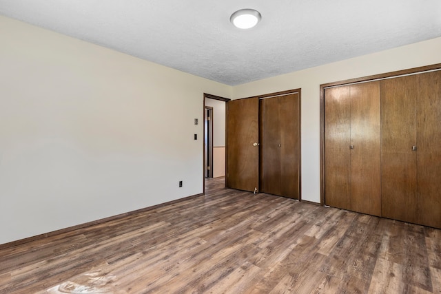 unfurnished bedroom featuring dark hardwood / wood-style floors and multiple closets