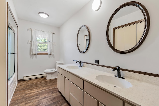 full bathroom with bath / shower combo with glass door, vanity, a baseboard radiator, hardwood / wood-style floors, and toilet