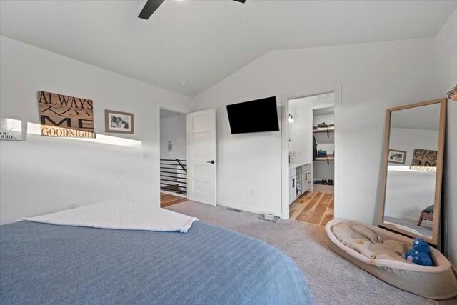 bedroom featuring connected bathroom, ceiling fan, a spacious closet, vaulted ceiling, and light carpet