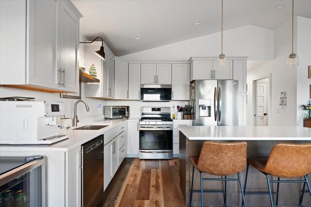 kitchen with sink, lofted ceiling, stainless steel appliances, and hanging light fixtures