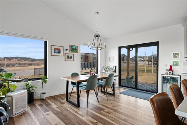 dining room with beverage cooler, an inviting chandelier, a mountain view, light hardwood / wood-style floors, and lofted ceiling