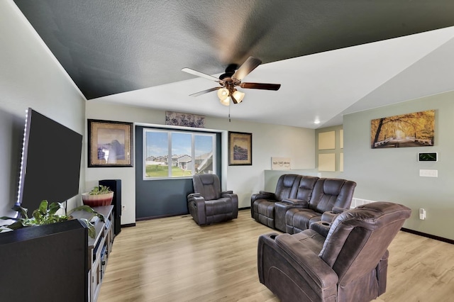 living room with ceiling fan, light hardwood / wood-style flooring, and vaulted ceiling