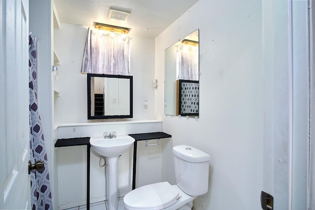 bathroom featuring sink, a textured ceiling, and toilet