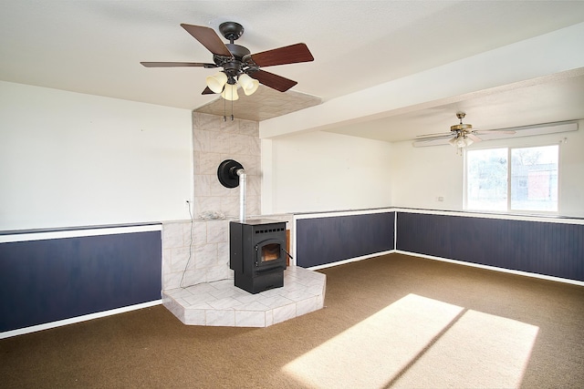 interior space with a wood stove, ceiling fan, and carpet floors