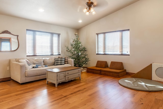 living room featuring ceiling fan, light hardwood / wood-style floors, and vaulted ceiling