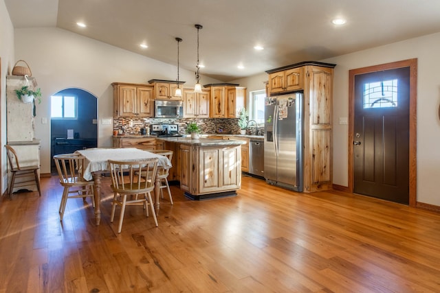 kitchen with tasteful backsplash, stainless steel appliances, pendant lighting, a center island, and lofted ceiling