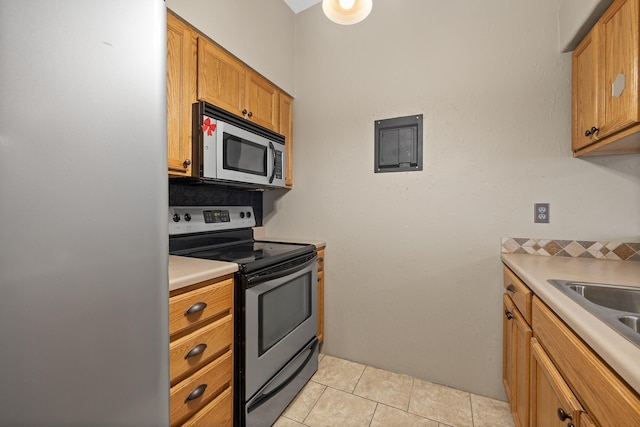 kitchen with appliances with stainless steel finishes, light tile patterned floors, and sink