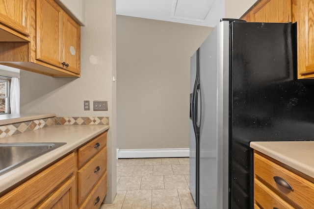 kitchen featuring stainless steel fridge, light tile patterned floors, and a baseboard heating unit