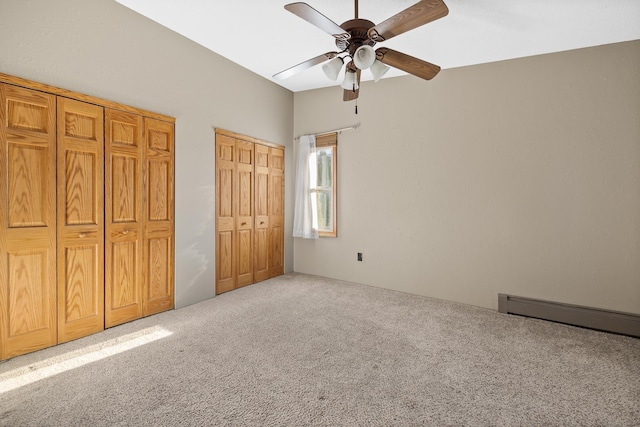 unfurnished bedroom with baseboard heating, multiple closets, ceiling fan, and carpet floors