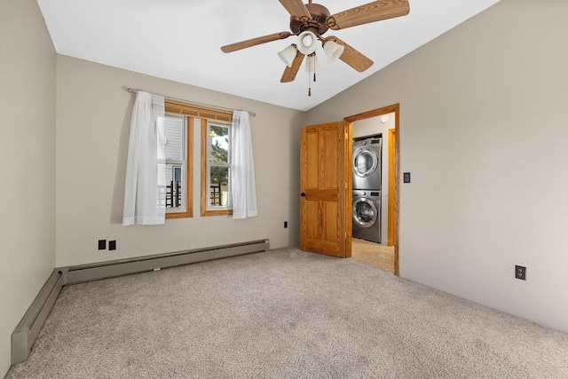 empty room with carpet, stacked washing maching and dryer, vaulted ceiling, baseboard heating, and ceiling fan