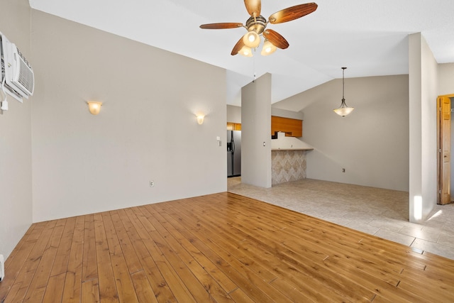 unfurnished living room featuring ceiling fan, light hardwood / wood-style flooring, and vaulted ceiling