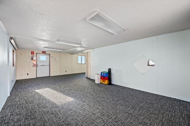 basement featuring dark colored carpet and a textured ceiling