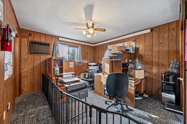 office featuring wooden walls, ceiling fan, and a textured ceiling