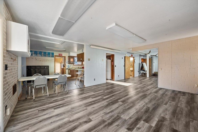 living room featuring hardwood / wood-style floors, a textured ceiling, and brick wall